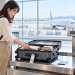 国内線の預け荷物を空港カウンターで計量する旅行者