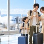 国内線の子供料金をスマートフォンで比較する空港の家族