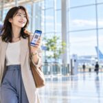 空港でスマートフォンの搭乗券を表示する旅行者（AI生成イメージ）