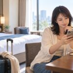 ホテルの客室でスマートフォンの予約内容を確認する旅行者