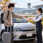 空港近くのレンタカー営業所で旅行者が車の鍵を返却するイメージ（AI生成・架空の人物と風景）